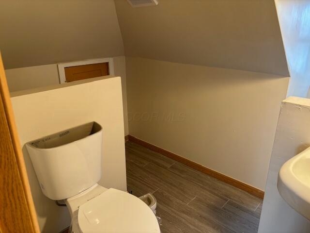 411 Berkeley Rd, Columbus, OH 43205 - bathroom featuring wood finished floors, toilet, baseboards, and vaulted ceiling