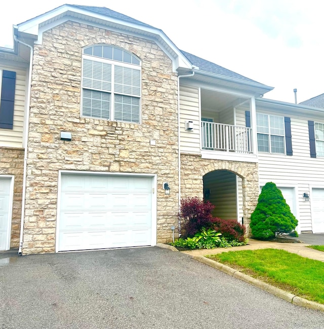 4960 Ivyvine Blvd, Dublin, OH 43016 - view of front of home featuring stone siding, a balcony, an attached garage, and driveway