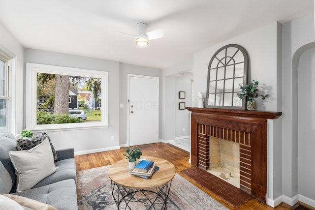 1052 Geers Ave, Columbus, OH 43206 - living room with wood finished floors, baseboards, a brick fireplace, and a ceiling fan