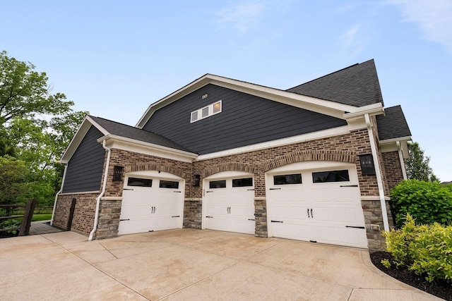 3624 Sparrow Ct, Hilliard, OH 43026 - view of side of property featuring concrete driveway, a garage, a shingled roof, and stone siding