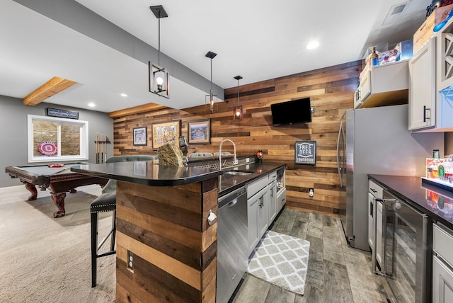 3624 Sparrow Ct, Hilliard, OH 43026 - kitchen featuring stainless steel dishwasher, wood walls, dark countertops, beamed ceiling, and wood finished floors