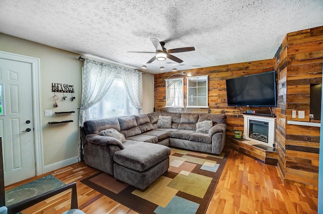 8448 Blue Lake Ave, Galloway, OH 43119 - living area featuring a ceiling fan, wood finished floors, wood walls, a textured ceiling, and baseboards