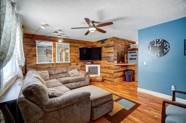 8448 Blue Lake Ave, Galloway, OH 43119 - living room featuring wooden walls, baseboards, a ceiling fan, wood finished floors, and a textured ceiling