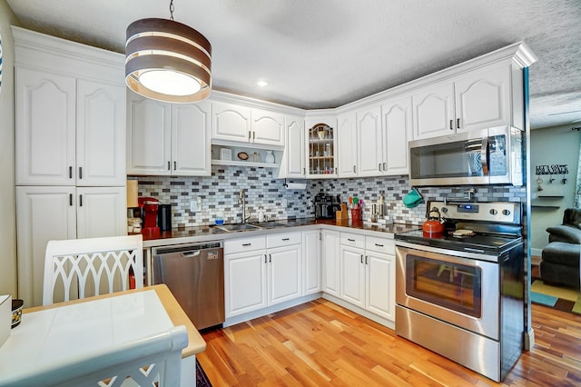8448 Blue Lake Ave, Galloway, OH 43119 - kitchen featuring stainless steel appliances, a sink, light wood-style flooring, backsplash, and a textured ceiling