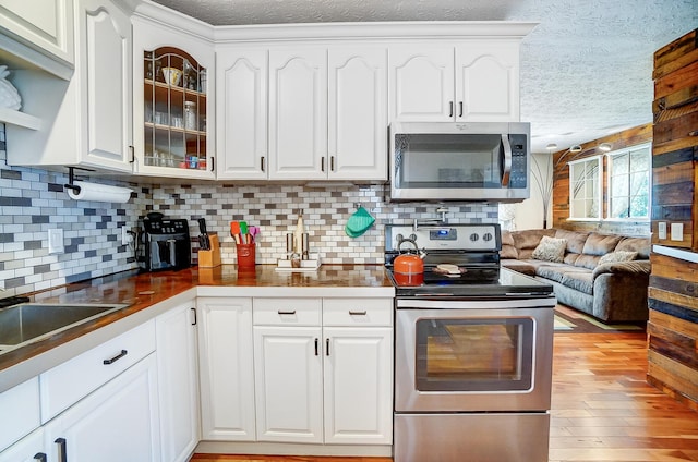 8448 Blue Lake Ave, Galloway, OH 43119 - kitchen featuring stainless steel appliances, a textured ceiling, white cabinets, glass insert cabinets, and backsplash