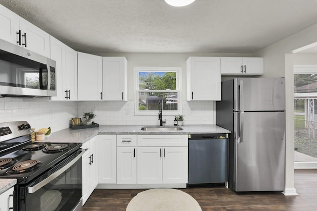 1465 Zenner Dr, Columbus, OH 43207 - kitchen with appliances with stainless steel finishes, a sink, healthy amount of natural light, dark wood-style flooring, and a textured ceiling