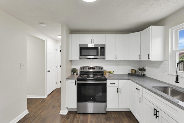 1465 Zenner Dr, Columbus, OH 43207 - kitchen with stainless steel appliances, a sink, backsplash, a textured ceiling, and dark wood-type flooring