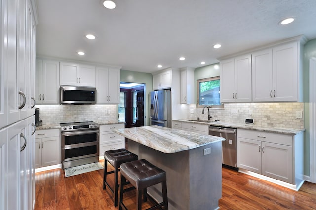 4359 Shire Cove Rd, Hilliard, OH 43026 - kitchen featuring appliances with stainless steel finishes, a sink, decorative backsplash, white cabinets, and a kitchen island