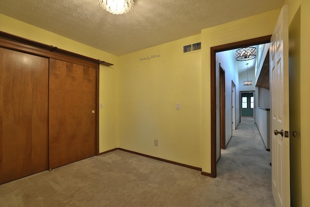 4359 Shire Cove Rd, Hilliard, OH 43026 - unfurnished bedroom featuring light carpet, a chandelier, a closet, and a textured ceiling