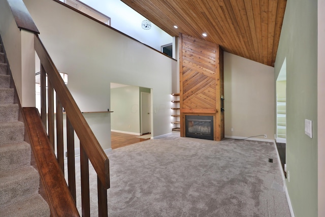 4359 Shire Cove Rd, Hilliard, OH 43026 - unfurnished living room featuring wood ceiling, carpet floors, high vaulted ceiling, stairs, and a glass covered fireplace