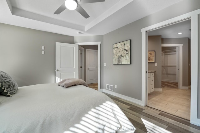 107 Willows End, Bellefontaine, OH 43311 - bedroom featuring light wood-style floors, a raised ceiling, baseboards, connected bathroom, and ceiling fan