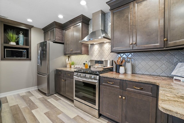 107 Willows End, Bellefontaine, OH 43311 - kitchen featuring appliances with stainless steel finishes, wall chimney exhaust hood, dark brown cabinetry, light wood-type flooring, and light stone counters