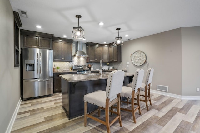 107 Willows End, Bellefontaine, OH 43311 - kitchen with appliances with stainless steel finishes, wall chimney exhaust hood, dark brown cabinetry, light wood-type flooring, and recessed lighting