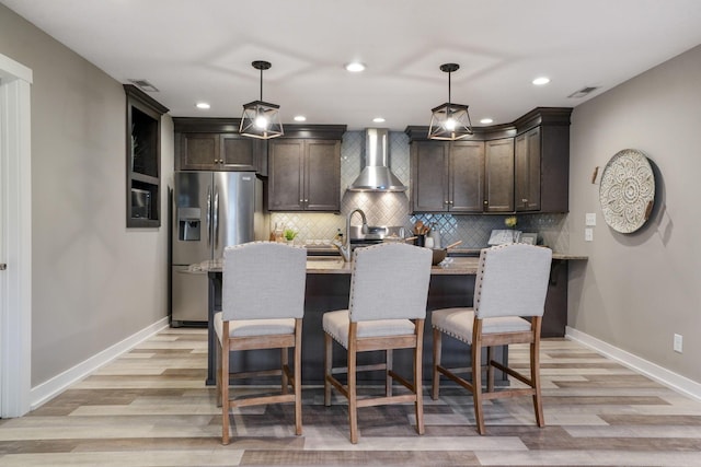 107 Willows End, Bellefontaine, OH 43311 - kitchen with wall chimney range hood, stainless steel refrigerator with ice dispenser, dark brown cabinetry, light wood-style flooring, and tasteful backsplash