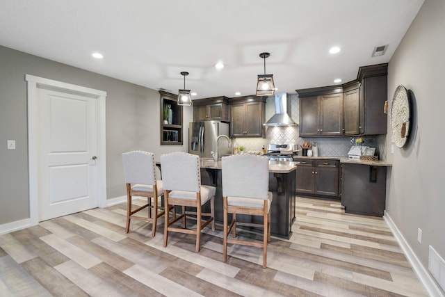 107 Willows End, Bellefontaine, OH 43311 - kitchen featuring stainless steel appliances, dark brown cabinets, wall chimney exhaust hood, light wood-style flooring, and recessed lighting
