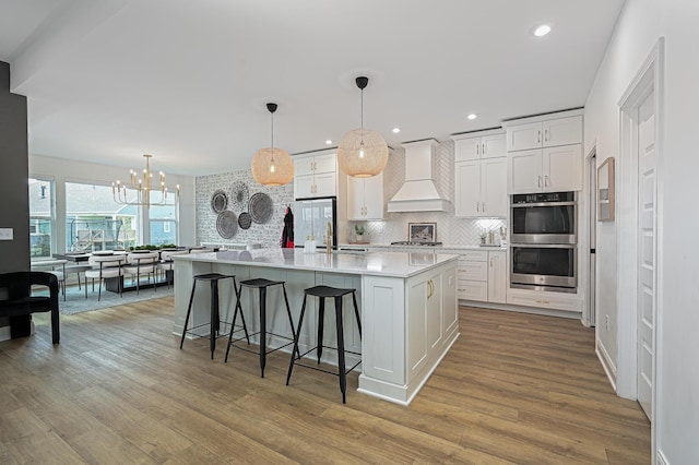 2733 Sycamore Trce, Hilliard, OH 43026 - kitchen featuring custom exhaust hood, appliances with stainless steel finishes, decorative backsplash, light countertops, and light wood finished floors