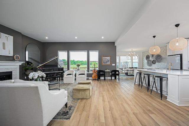 2733 Sycamore Trce, Hilliard, OH 43026 - living area featuring light wood-type flooring, a stone fireplace, recessed lighting, and a chandelier