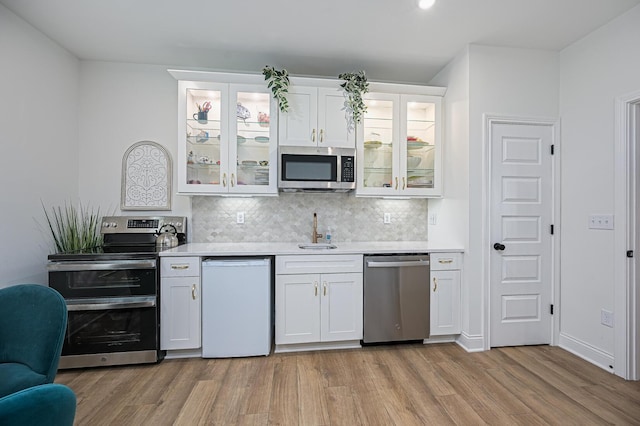 2733 Sycamore Trce, Hilliard, OH 43026 - kitchen featuring stainless steel appliances, a sink, light wood-style flooring, light countertops, and decorative backsplash