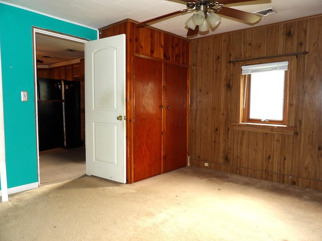 938 Meadowview Ave, Lancaster, OH 43130 - unfurnished bedroom featuring freestanding refrigerator, a closet, wood walls, carpet flooring, and ceiling fan