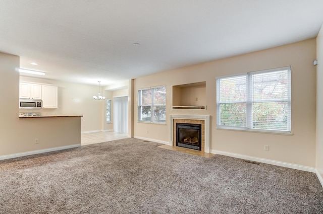 2697 Rinaldi Dr, Columbus, OH 43219 - unfurnished living room featuring a chandelier, light carpet, a tiled fireplace, and plenty of natural light