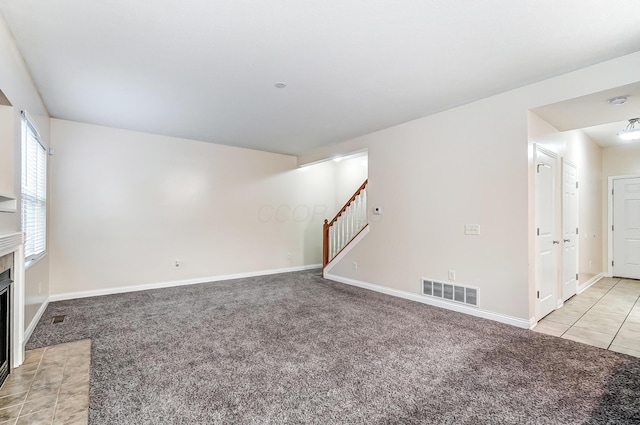 2697 Rinaldi Dr, Columbus, OH 43219 - unfurnished living room with stairway, light colored carpet, a fireplace with flush hearth, and baseboards