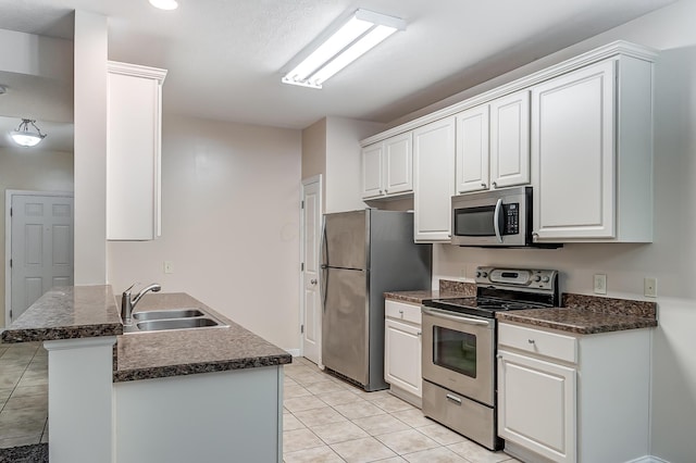2697 Rinaldi Dr, Columbus, OH 43219 - kitchen with appliances with stainless steel finishes, a sink, dark countertops, light tile patterned floors, and white cabinetry