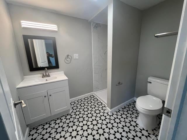 79 N Main St, Jeffersonville, OH 43128 - bathroom featuring toilet, vanity, baseboards, and tiled shower