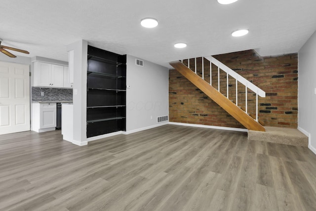 2505 Burgandy Ln Unit C, Columbus, OH 43232 - unfurnished living room featuring baseboards, brick wall, light wood-style flooring, stairs, and ceiling fan