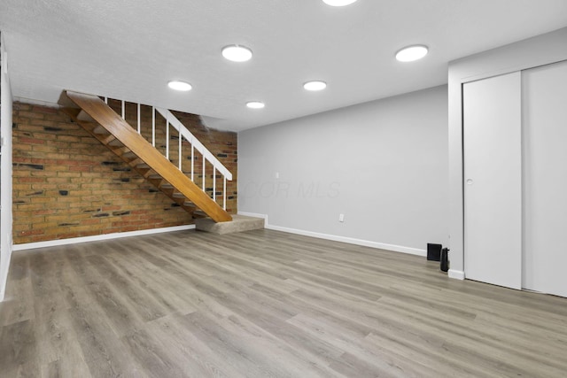2505 Burgandy Ln Unit C, Columbus, OH 43232 - unfurnished living room with brick wall, baseboards, wood finished floors, stairs, and recessed lighting