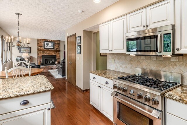 5584 Tangarey Ct, Columbus, OH 43235 - kitchen featuring appliances with stainless steel finishes, dark wood finished floors, backsplash, open floor plan, and a textured ceiling