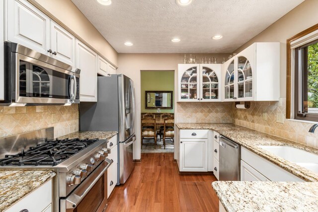 5584 Tangarey Ct, Columbus, OH 43235 - kitchen featuring appliances with stainless steel finishes, white cabinetry, wood finished floors, light stone counters, and recessed lighting