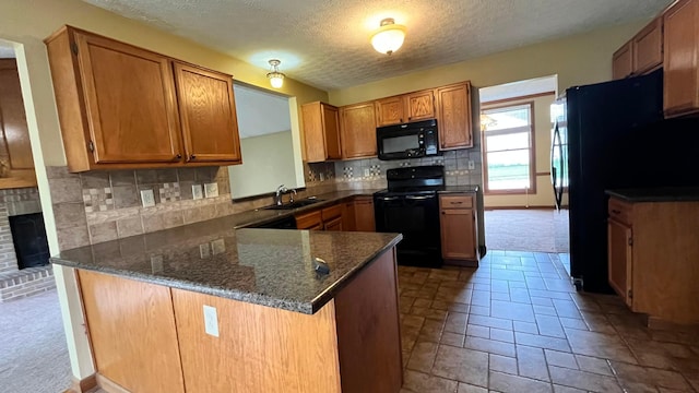5459 Red Wynne Ln, Hilliard, OH 43026 - kitchen featuring black appliances, a peninsula, a textured ceiling, brown cabinetry, and tasteful backsplash