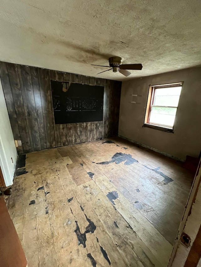 527 N 15th St, Coshocton, OH 43812 - unfurnished living room featuring a textured ceiling, a ceiling fan, and wooden walls