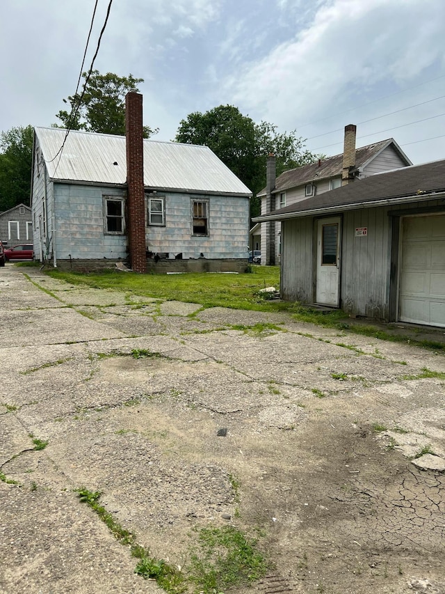 527 N 15th St, Coshocton, OH 43812 - back of house with driveway, a chimney, and metal roof