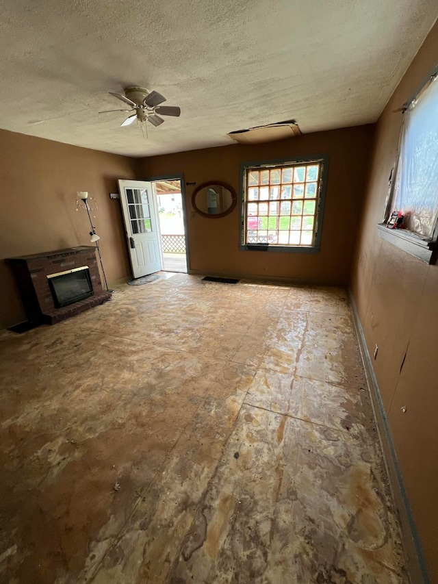 527 N 15th St, Coshocton, OH 43812 - unfurnished living room featuring healthy amount of natural light, a textured ceiling, a fireplace, and ceiling fan