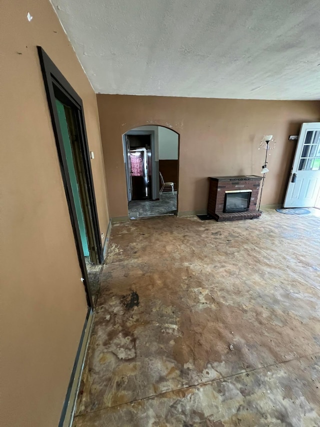 527 N 15th St, Coshocton, OH 43812 - unfurnished living room with arched walkways, a textured ceiling, baseboards, and a fireplace