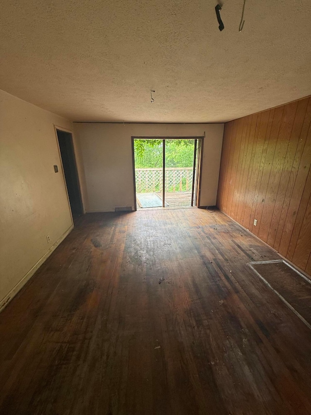 527 N 15th St, Coshocton, OH 43812 - unfurnished room featuring a textured ceiling, hardwood / wood-style flooring, wooden walls, and baseboards