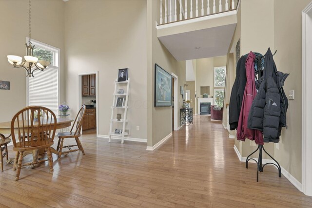 8708 Belworth Sq, New Albany, OH 43054 - dining space with a towering ceiling, a chandelier, light wood finished floors, baseboards, and a glass covered fireplace