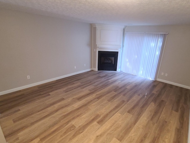 6768 Axtel Dr Unit 15B, Canal Winchester, OH 43110 - unfurnished living room with a fireplace, wood finished floors, a textured ceiling, and baseboards
