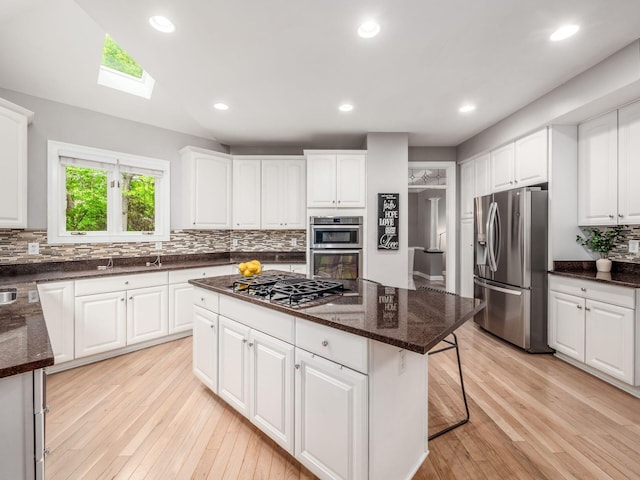 2655 Aikin Cir S, Lewis Center, OH 43035 - kitchen featuring stainless steel appliances, a skylight, a kitchen bar, tasteful backsplash, and dark stone countertops