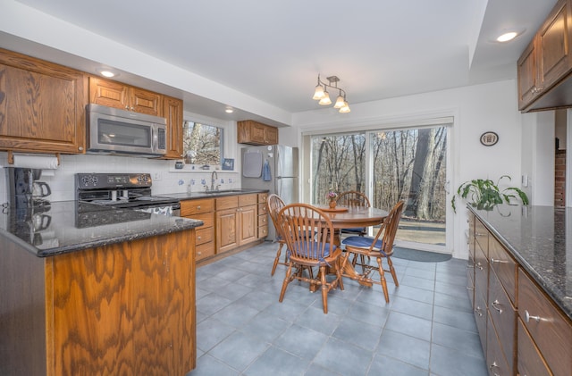 213 Kokosing Dr, Gambier, OH 43022 - kitchen featuring stainless steel appliances, a sink, tasteful backsplash, dark stone countertops, and brown cabinetry