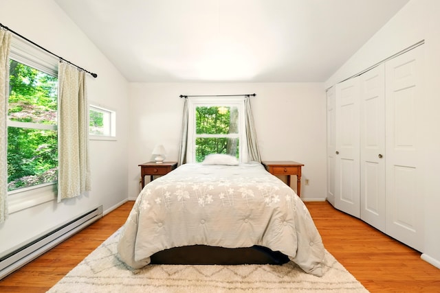 213 Kokosing Dr, Gambier, OH 43022 - bedroom featuring baseboard heating, lofted ceiling, multiple windows, light wood-style floors, and a closet