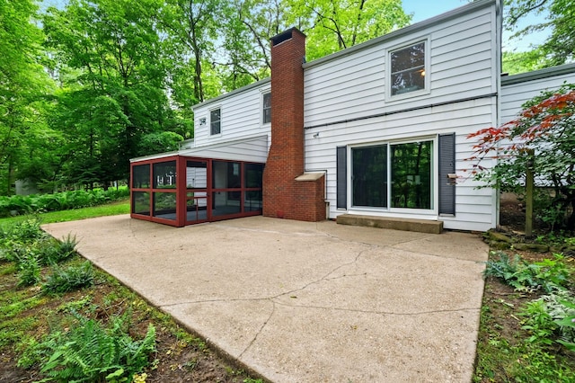 213 Kokosing Dr, Gambier, OH 43022 - rear view of property featuring a sunroom, a patio area, and a chimney
