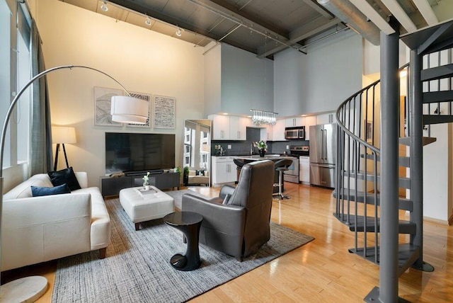 110 N 3rd St Unit 709, Columbus, OH 43215 - living room with a towering ceiling, rail lighting, light wood-style floors, stairway, and beamed ceiling