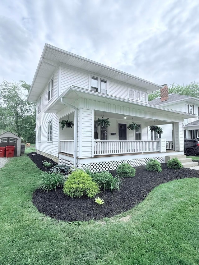 84 E 5th St, London, OH 43140 - view of front of home with covered porch, a front yard, and an outbuilding