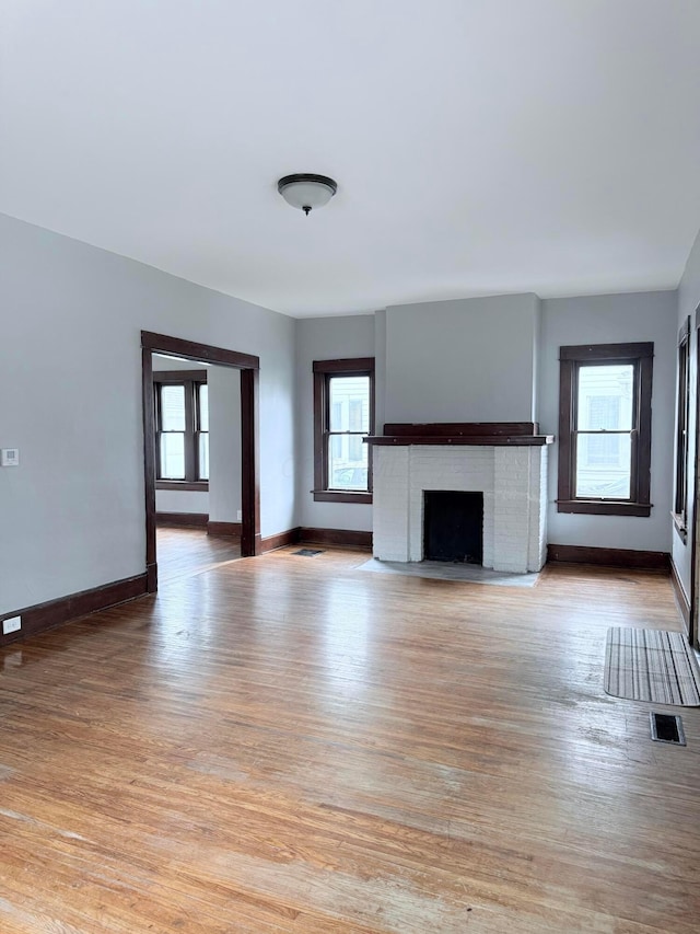 84 E 5th St, London, OH 43140 - unfurnished living room with plenty of natural light, light wood-type flooring, a brick fireplace, and baseboards