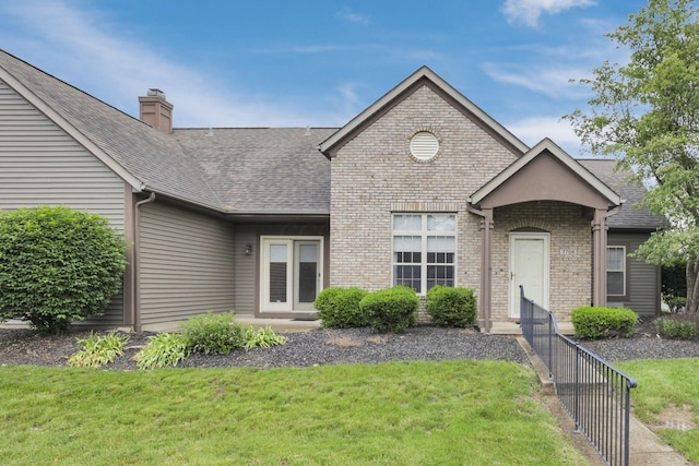 7706 Redman Ln, Reynoldsburg, OH 43068 - view of front of home with a front yard, a chimney, a shingled roof, and brick siding
