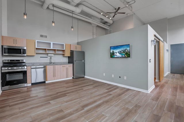 60 E Spring St Unit 327, Columbus, OH 43215 - kitchen with appliances with stainless steel finishes, light brown cabinets, a high ceiling, open shelves, and a sink