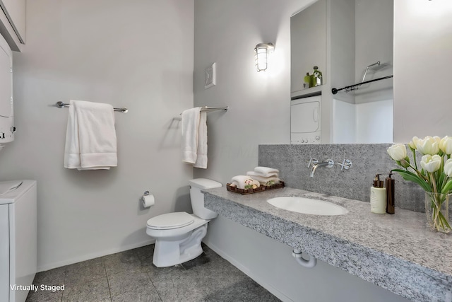 60 E Spring St Unit 327, Columbus, OH 43215 - bathroom featuring a sink, toilet, stacked washer / drying machine, and baseboards