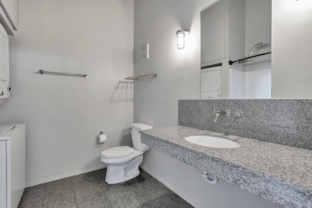 60 E Spring St Unit 327, Columbus, OH 43215 - bathroom featuring a sink, toilet, baseboards, and stacked washer / dryer